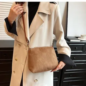 Brown suede tote bag styled with cream coat and vintage artistic background props