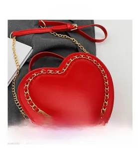 Close-up of heart-shaped red glossy bag featuring decorative gold chain link edge detail