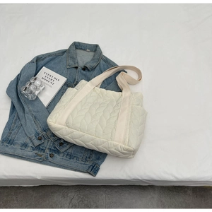 Detail of white quilted tote bag with leaf-shaped stitching and cotton ribbon handles