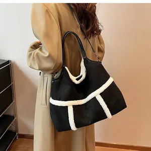 Detailed view of black suede tote bag with white faux shearling trim and leather handles