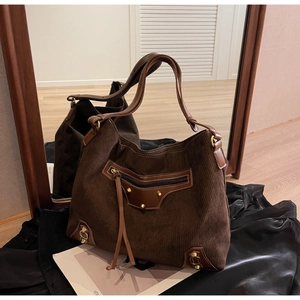 Detail of coffee corduroy tote bag with brown leather trim and metallic rivet accents