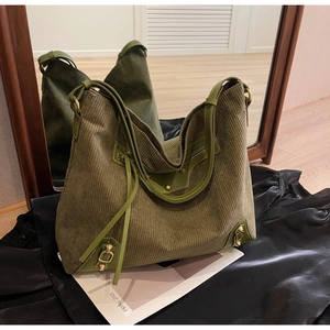 Detail of olive green corduroy tote bag with fringe accents and leather handle texture