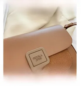Detail shot of the square metal hardware buckle on a brown leather crossbody handbag