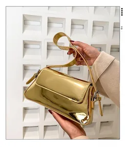 Detail of glossy metallic gold patent leather baguette bag with reflective mirror finish