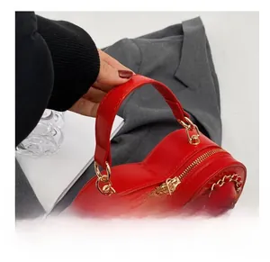 Detail shot of a red heart-shaped handbag with pebbled leather and gold-tone chain strap