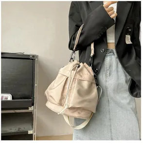 Detail of light beige nylon bucket bag with drawstring closure and woven shoulder strap