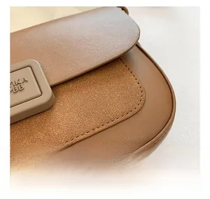 Detail shot of brown leather shoulder bag with embossed MIKA BB square buckle and stitching