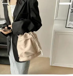 Detail of a beige nylon bucket bag with drawstring closure worn with a black blazer