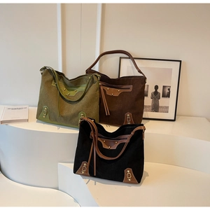 Detailed view of corduroy tote bags with vintage leather straps on a white podium