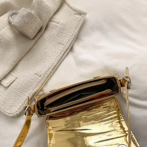 Detailed interior of a gold glossy crossbody bag with zipper compartment and silver buckle