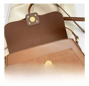 Detail showing the magnetic button closure on the brown vintage leather crossbody bag