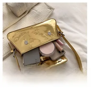 Detail view of gold mirror finish baguette bag interior with phone and cosmetics
