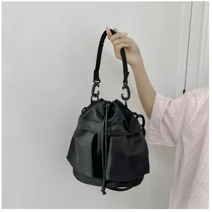 Detail of black nylon drawstring bucket bag with utility pockets and wide strap