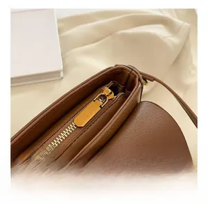 Close-up of golden metal zipper and pebble grain leather on caramel brown crossbody bag
