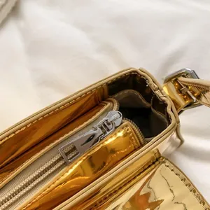 Detail shot showing the metallic gold patent leather texture and zipper of the baguette bag