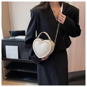 Close-up of heart-shaped handbag in cream white leather with gold chain detail