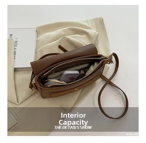 Detail view of brown leather square bag interior capacity showing phone and makeup