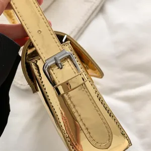 Detailed close-up of glossy gold mirror finish patent leather with silver metal buckle