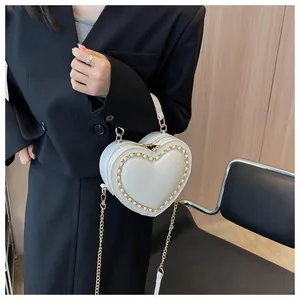 Detail of cream heart bag with pearl chain trim worn by a model in a black blazer
