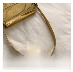 Close-up of the smooth golden patent leather handle on a glossy designer baguette bag
