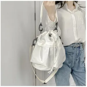 Detail of white nylon bucket bag with drawstring closure and black carabiner hardware