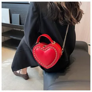 Detailed view of red heart-shaped bag with gold chain trim on a dark suit
