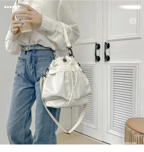 Detailed view of a white nylon bucket bag with drawstring closure and slim shoulder strap
