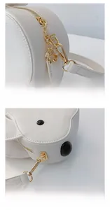 Détail du sac blanc avec fermetures éclair dorées et pendentif trèfle en métal poli