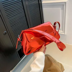Detailed close-up of glossy red patent leather bag texture with metallic buckle and strap
