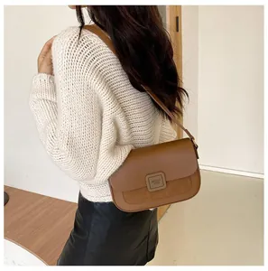 Detail of dark brown leather crossbody bag featuring mixed textures and magnetic clasp