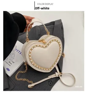 Detailed view of off-white heart-shaped bag with woven gold chain strap and top handle