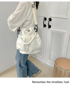 Detail view of white nylon bucket bag showing wide fabric strap and drawstring closure