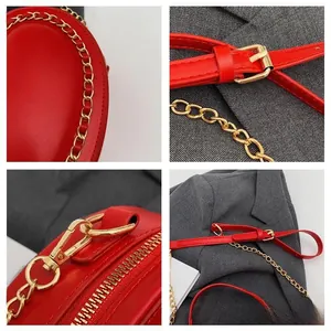 Detail view of red leather handbag showing golden chain, metal zipper and adjustable strap