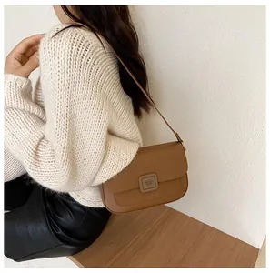 Close-up of brown leather crossbody bag featuring contrasting suede flap and retro buckle