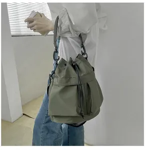 Detail of army green nylon bucket bag with drawstring closure and functional pockets