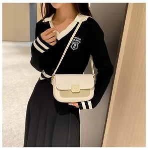 Model wearing a minimalist cream and sage green crossbody bag with gold square buckle clasp