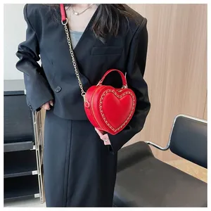 Detailed view of red heart-shaped leather crossbody bag with woven gold chain trim