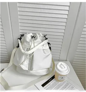 Detail of white nylon bucket bag with drawstring closure and black metal hardware hook