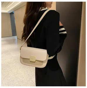 Detail view of cream crossbody bag featuring a contrast panel and square logo buckle