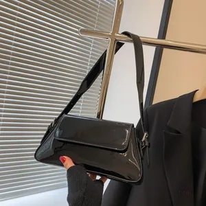 Detail of glossy black patent leather baguette bag hanging on a silver metallic rack