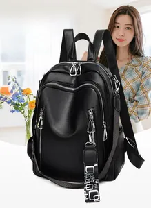 Side view of a black leather backpack with silver zippers and a geometric woven strap