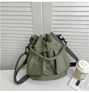 Detail of army green nylon bucket bag with drawstring closure and black wide strap