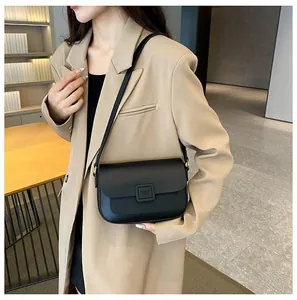 Side view of model wearing a black leather crossbody bag with square metal buckle detail
