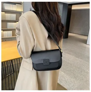 Rear view of a chic black leather crossbody bag with a square buckle on a model