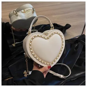 Detail of a heart-shaped cream handbag with elegant gold chain trim and top handle