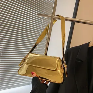 Detail of metallic gold glossy baguette bag with mirror finish and slim shoulder strap