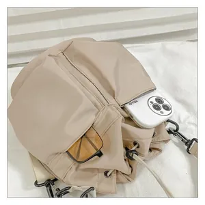 Detail view of beige nylon bucket bag featuring drawstring closure and side pockets