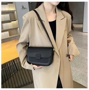 Detail of black matte leather shoulder bag featuring a square buckle and adjustable strap