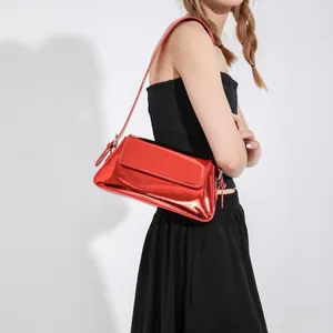Macro shot of glossy red patent leather finish and adjustable strap on baguette bag
