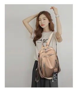 Detail view of stylish beige backpack with multiple zippers and decorative strap ribbons